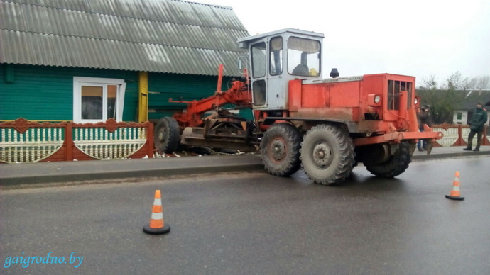 грейдер протаранил забор и дом